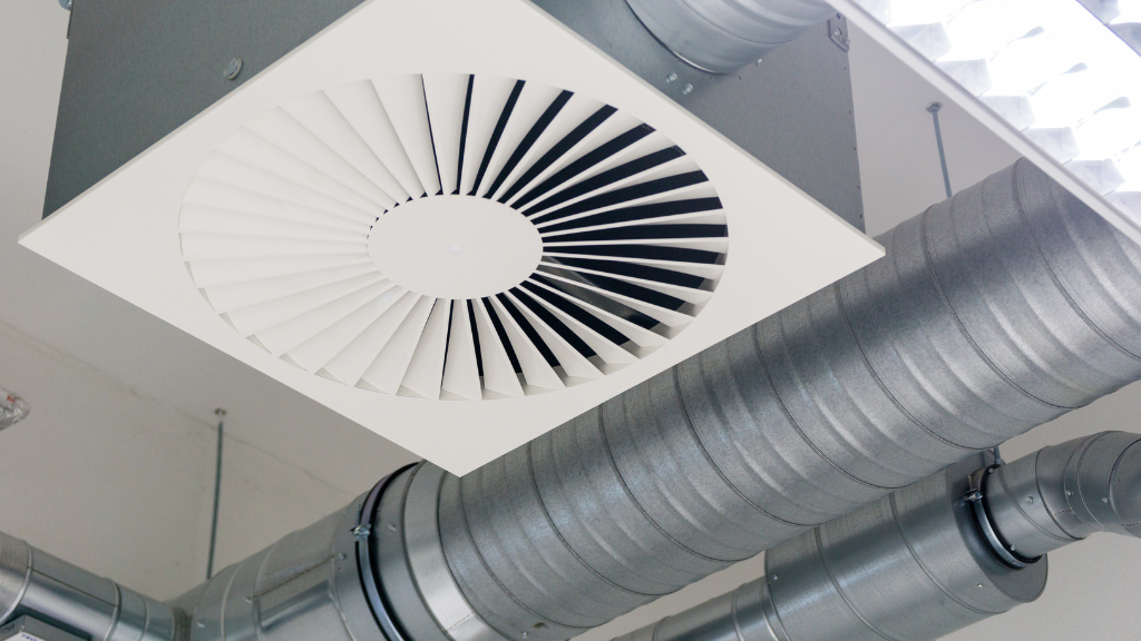 Lüftungsanlage mit Luftauslass und Metallrohren an der Decke. Detailaufnahme für professionelle Lüftungsreinigung